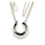 Mini sterling silver horseshoe shaped pendant filled with emerald, amazonite, blue tourmaline, and green amethyst gemstones, with a gold filled and sterling dot chain with pyrite accents necklace
