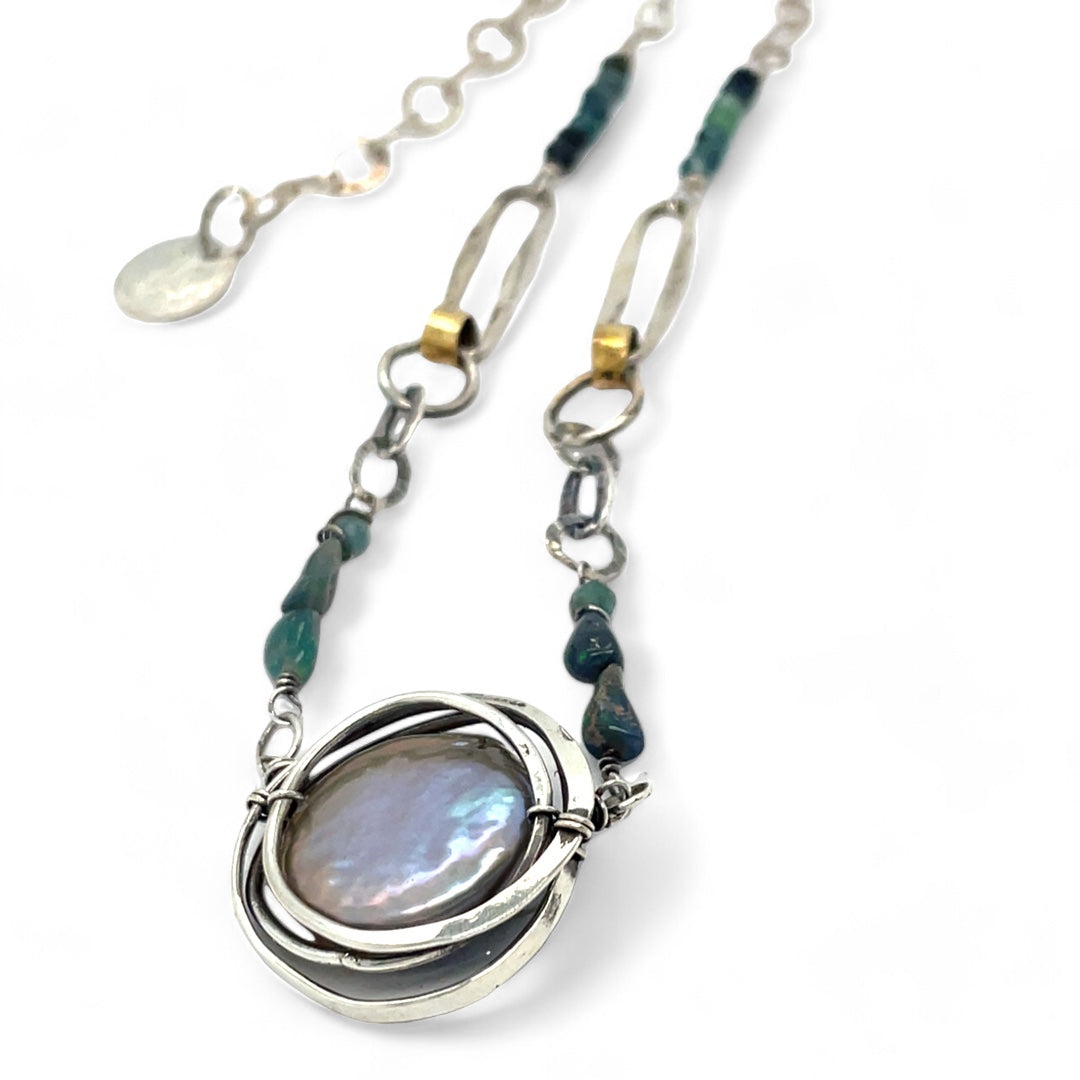 A sterling silver chain link necklace with a blue purple fresh water pearl coin in a hammered silver knot pendant, accented with blue opal and blue tourmaline gemstones