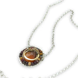 Necklace with a circular pendant featuring a central honey chalcedony stone and smaller mookaite jasper gemstones surrounding brass hammered wire