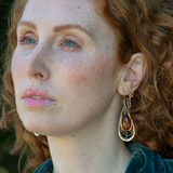 Sterling silver handmade drop earrings with carnelian, pyrite, blue fresh water pearl, red cubic zirconia, and green amethyst carved hand within layers of gold filled and brass wires