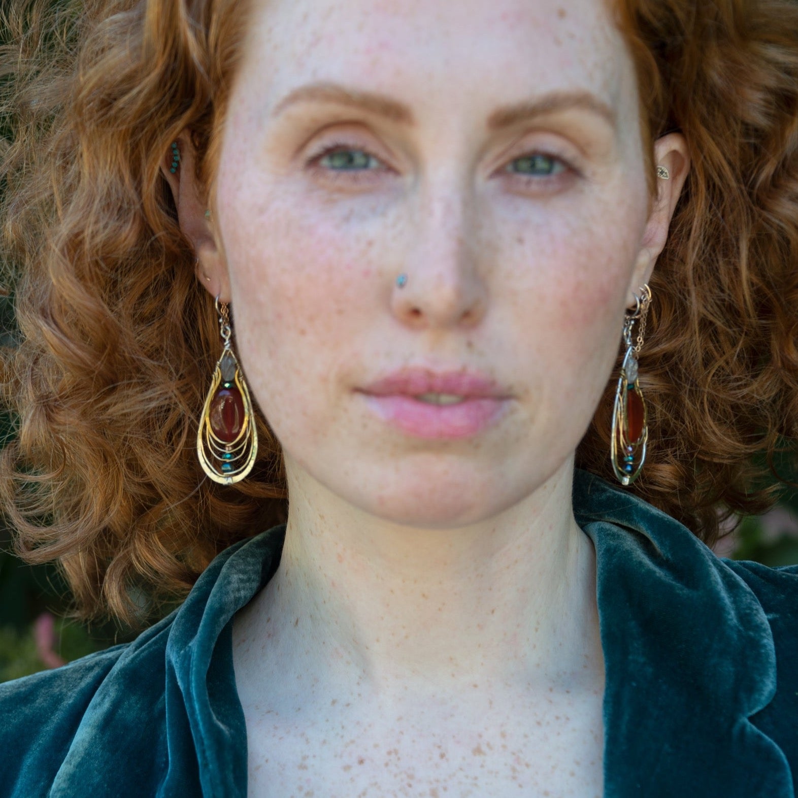 Sterling silver handmade drop earrings with carnelian, pyrite, blue fresh water pearl, red cubic zirconia, and green amethyst carved hand within layers of gold filled and brass wires