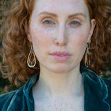 Sterling silver handmade drop earrings with carnelian, pyrite, blue fresh water pearl, red cubic zirconia, and green amethyst carved hand within layers of gold filled and brass wires