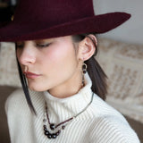 A pair of cascade style garnet earrings with faceted sphere gemstones, handmade brass hoops, and suspending oxidized sterling silver chains with a deep red freshwater pearl.