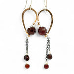 A pair of cascade style garnet earrings with faceted sphere gemstones, handmade brass hoops, and suspending oxidized sterling silver chains with a deep red freshwater pearl.