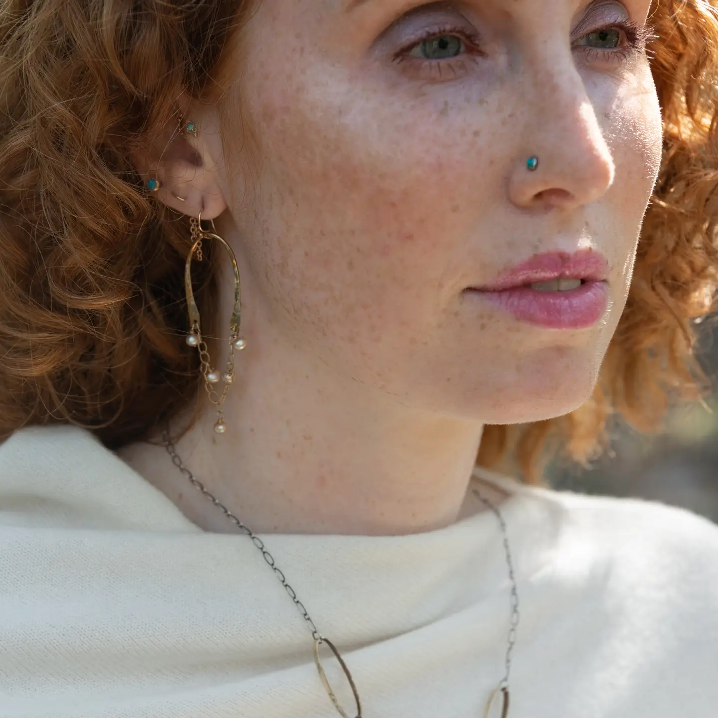 Shiny brass arch earrings with gold-filled chain cascading with champagne colored fresh water pearls.
