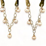 Shiny brass arch earrings with gold-filled chain cascading with champagne colored fresh water pearls.