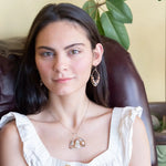 Pink and champagne colored fresh water pearls combined with a peach opalescent faceted drop gemstone sit inside a brass stamped marquise earring with sterling silver accent