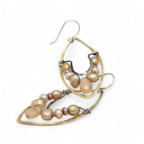 Pink and champagne colored fresh water pearls combined with a peach opalescent faceted drop gemstone sit inside a brass stamped marquise earring with sterling silver accent