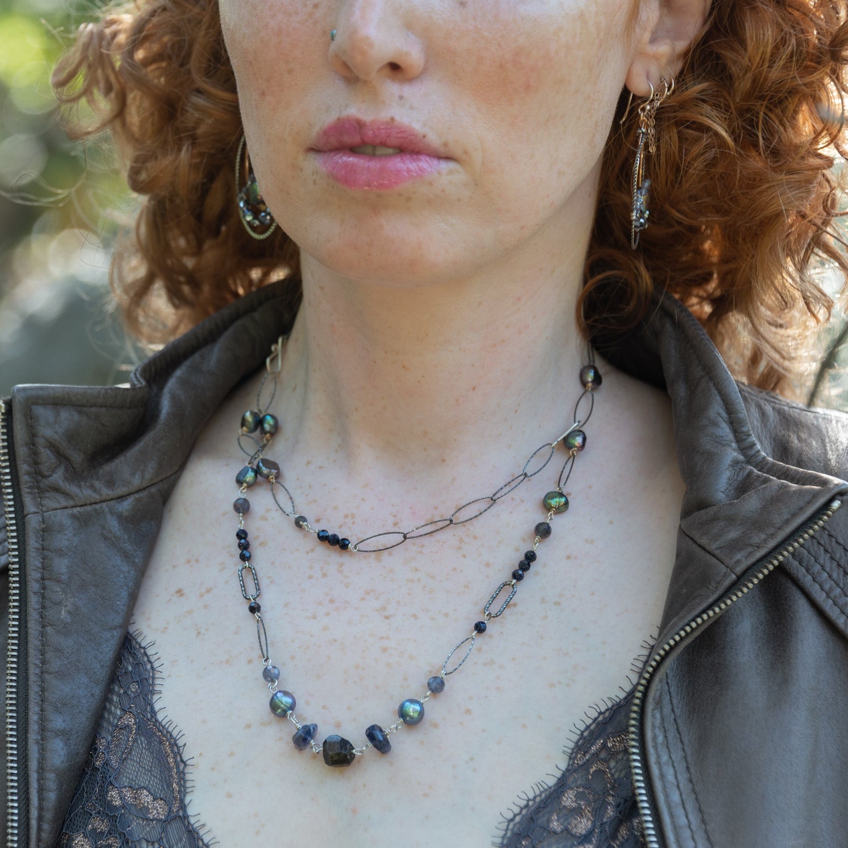 Iolite nugget gemstones, blue/purple fresh water pearls, and blue goldstone are joined together with darkened sparkly sterling silver links to create a long necklace able to layer