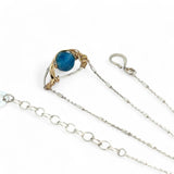 a singular faceted apatite gemstone is held in layered of hammered gold filled wire on a mini sterling silver paisley necklace