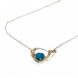 a singular faceted apatite gemstone is held in layered of hammered gold filled wire on a mini sterling silver paisley necklace
