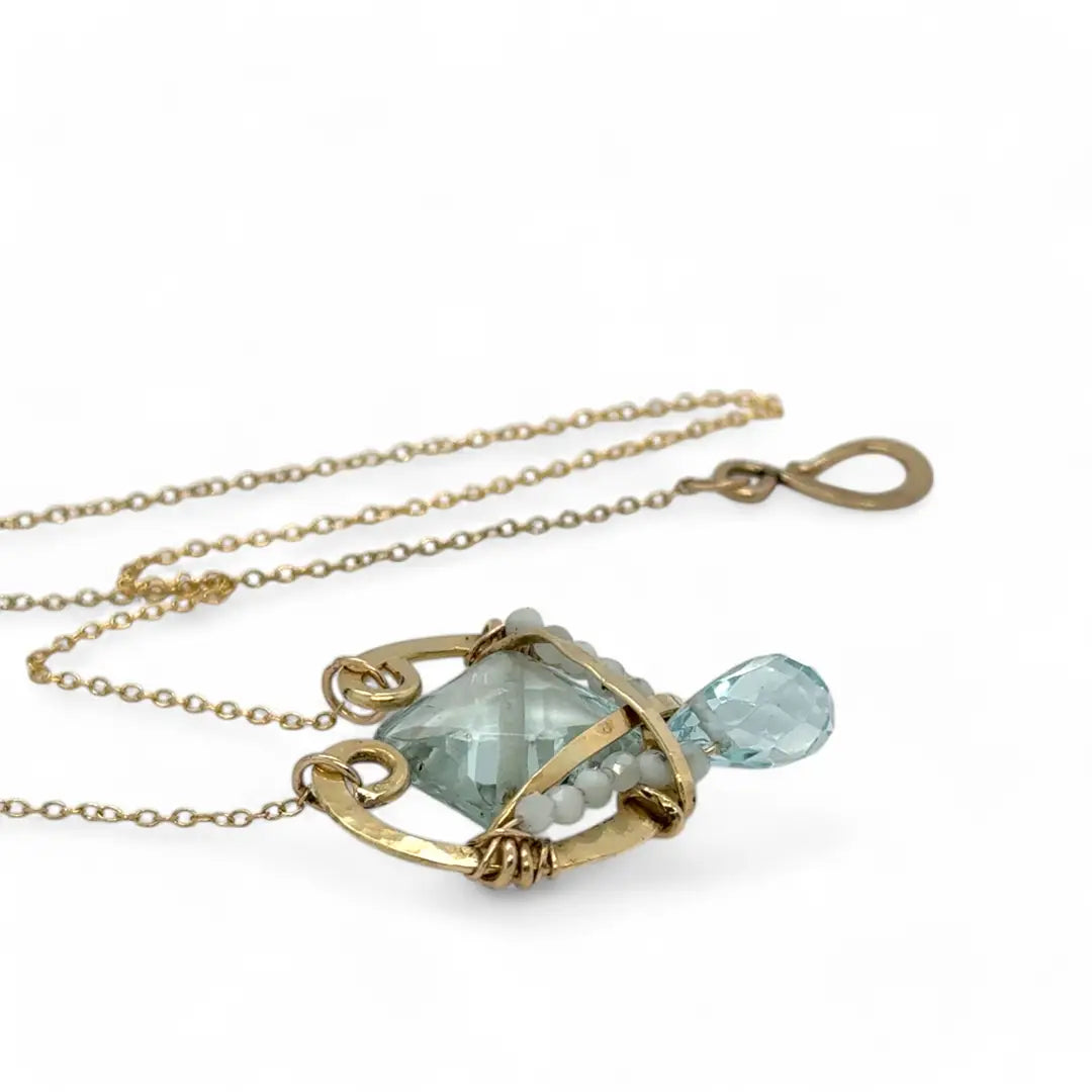 brass hammered mini pendant with aqua quartz tile lined in light blue cat's eye tiny gemstones with a faceted blue quartz drop at the bottom on gold filled chain necklace