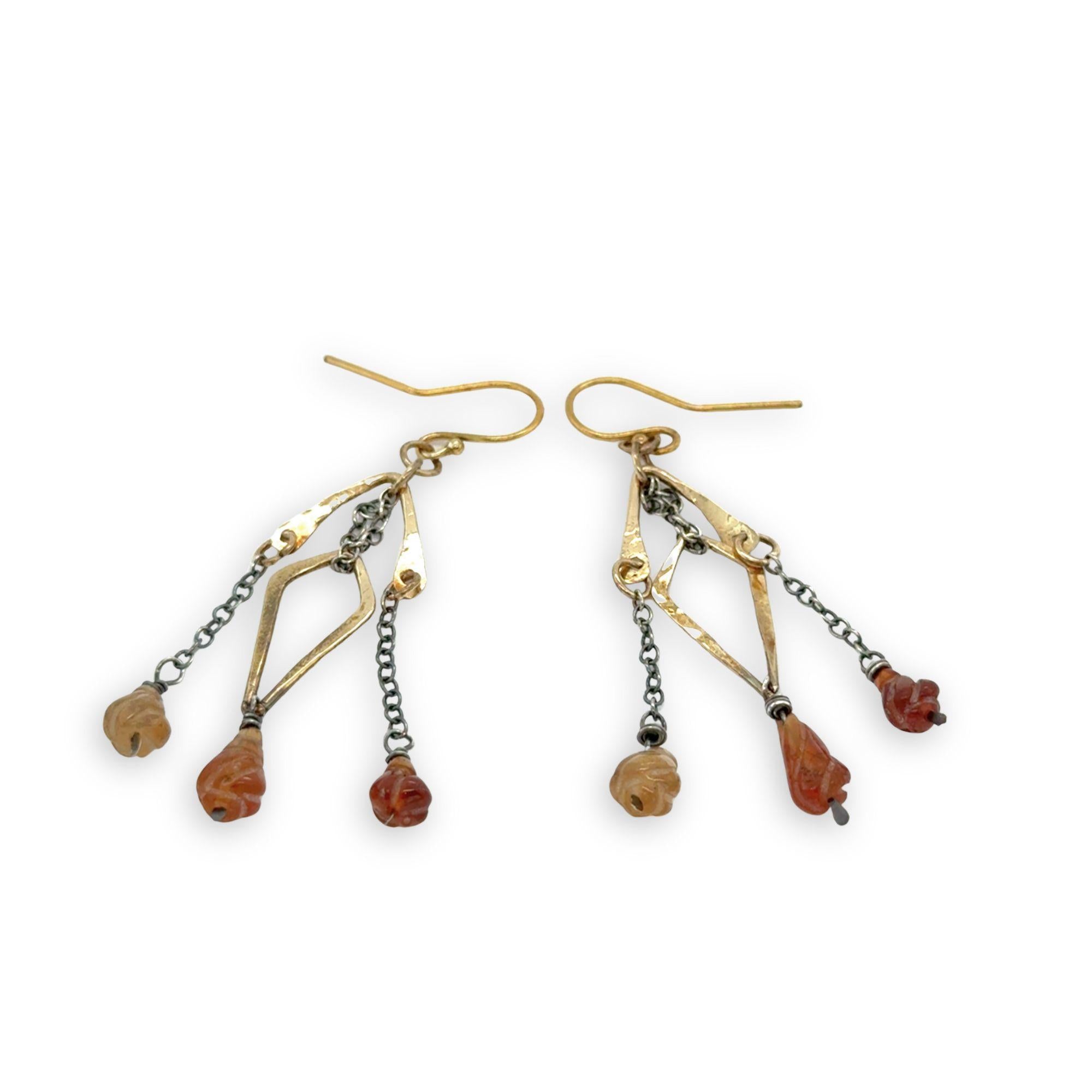 fire shaped carved hessonite garnet gemstones dangle from dark sterling silver delicate chain and brass arches and diamond earrings