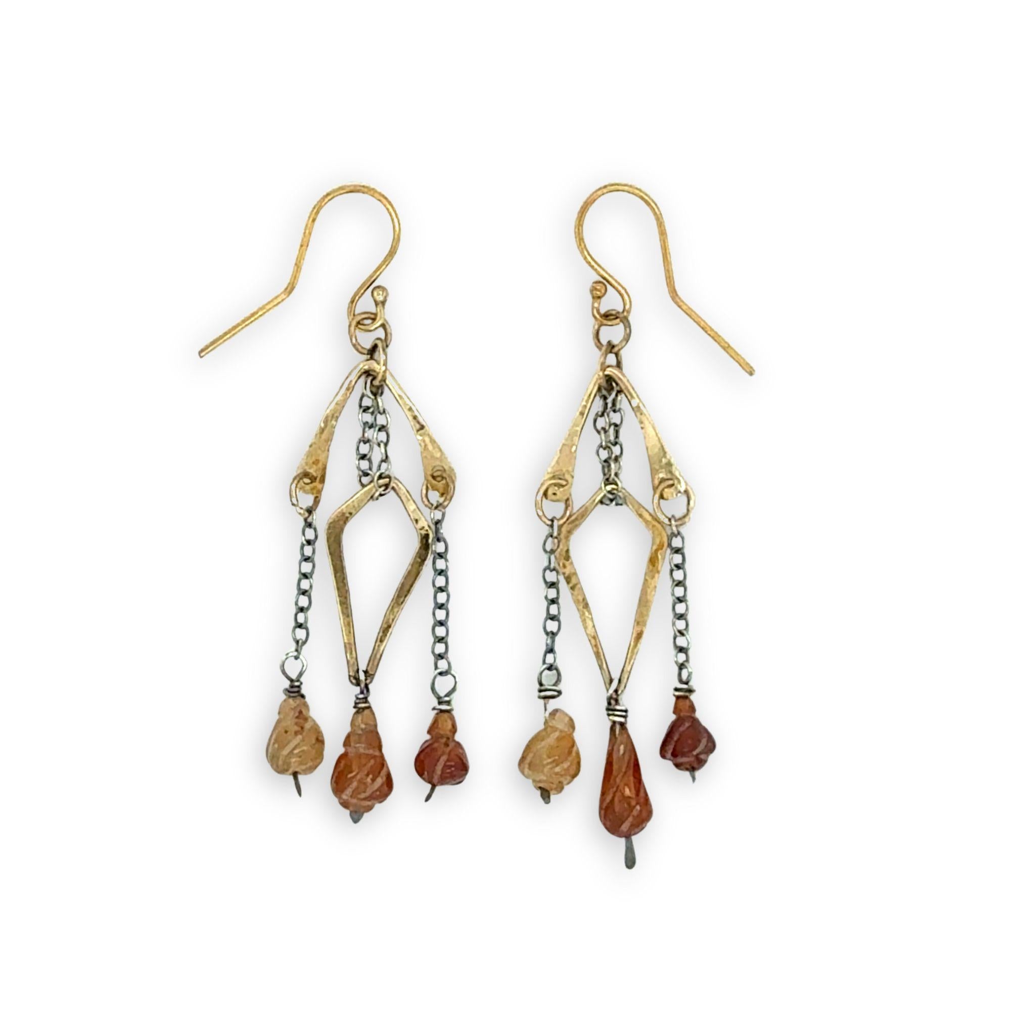 fire shaped carved hessonite garnet gemstones dangle from dark sterling silver delicate chain and brass arches and diamond earrings