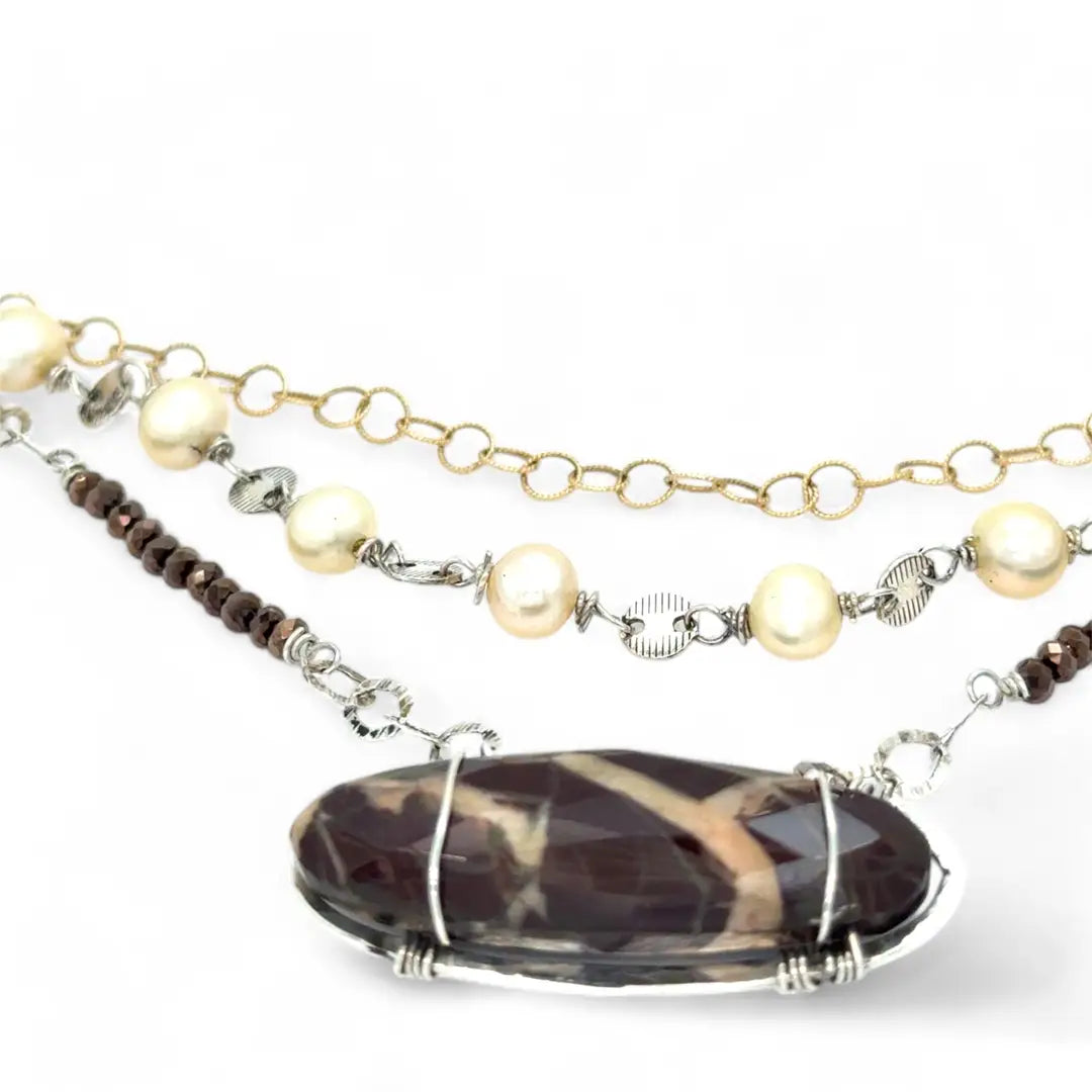 Brown oval jasper held in sterling silver is layered with fresh water pearl, gold filled chain, and pyrite gemstones to form an already layered necklace