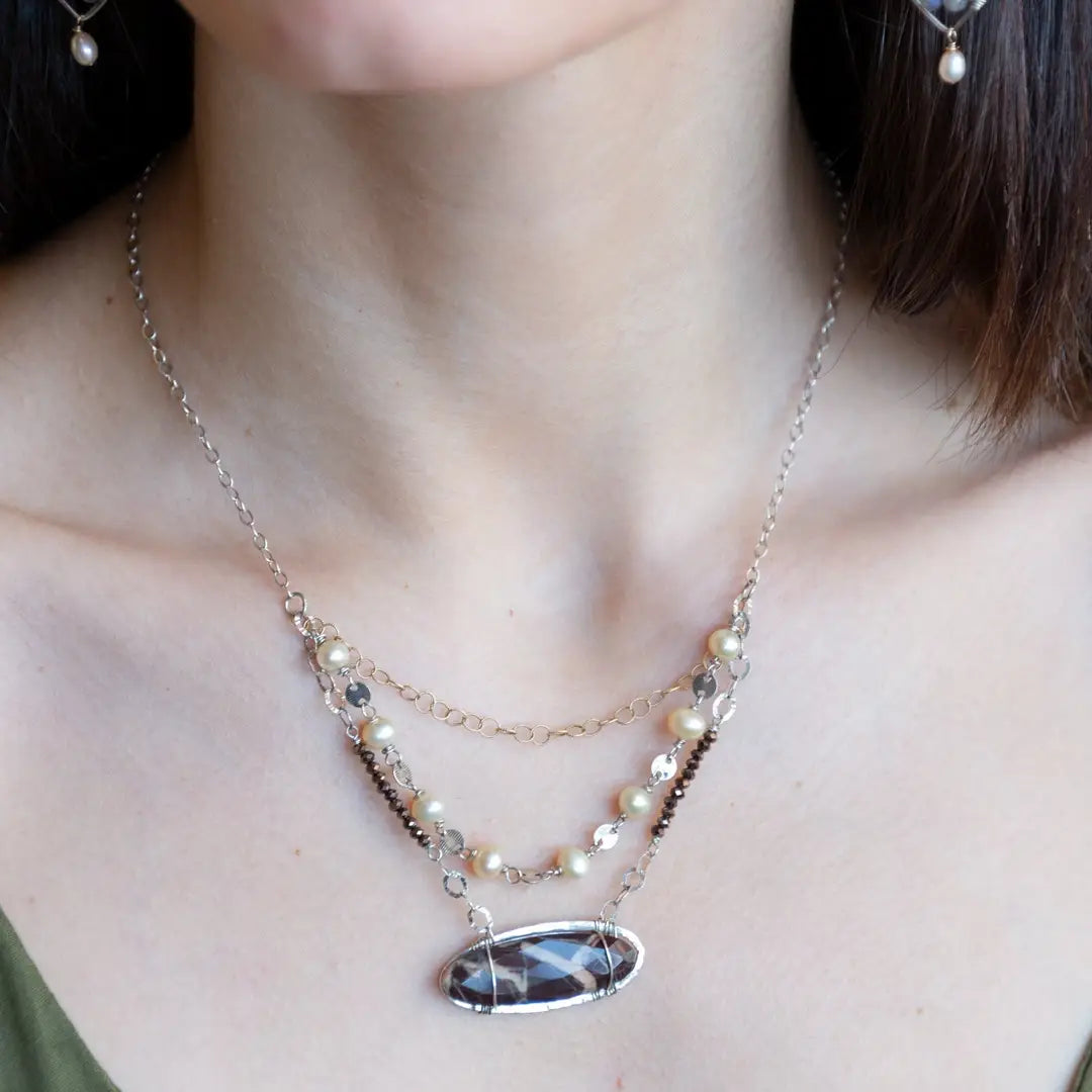 Brown oval jasper held in sterling silver is layered with fresh water pearl, gold filled chain, and pyrite gemstones to form an already layered necklace