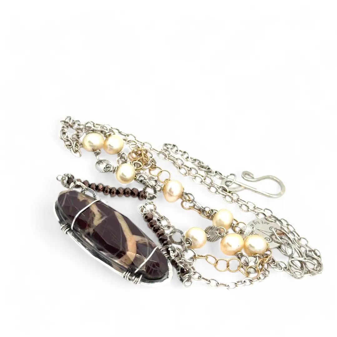 Brown oval jasper held in sterling silver is layered with fresh water pearl, gold filled chain, and pyrite gemstones to form an already layered necklace