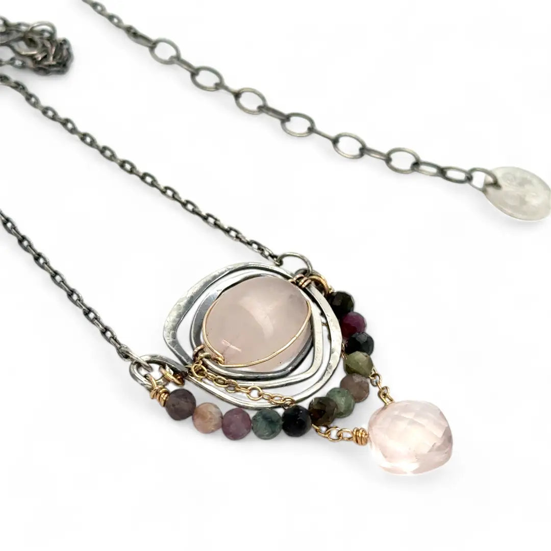 a smooth rose quartz oval is held in an oxidized sterling silver spiral pendant accompanied by tourmaline gemstones with a faceted rose quartz gemstone drop with gold filled delicate chain accent necklace