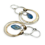 Blue crystal drop held within circles of brass stamped rings handing on a sterling silver hoop