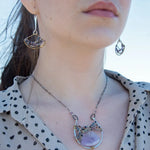 A necklace with a braided design featuring amethyst gemstones and a mix of natural gemstones, with a hammered brass and sterling silver twist. The pendant is accompanied by an oxidized sterling silver chain and a handmade clasp.