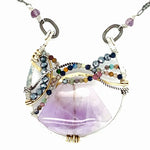 A necklace with a braided design featuring amethyst gemstones and a mix of natural gemstones, with a hammered brass and sterling silver twist. The pendant is accompanied by an oxidized sterling silver chain and a handmade clasp.