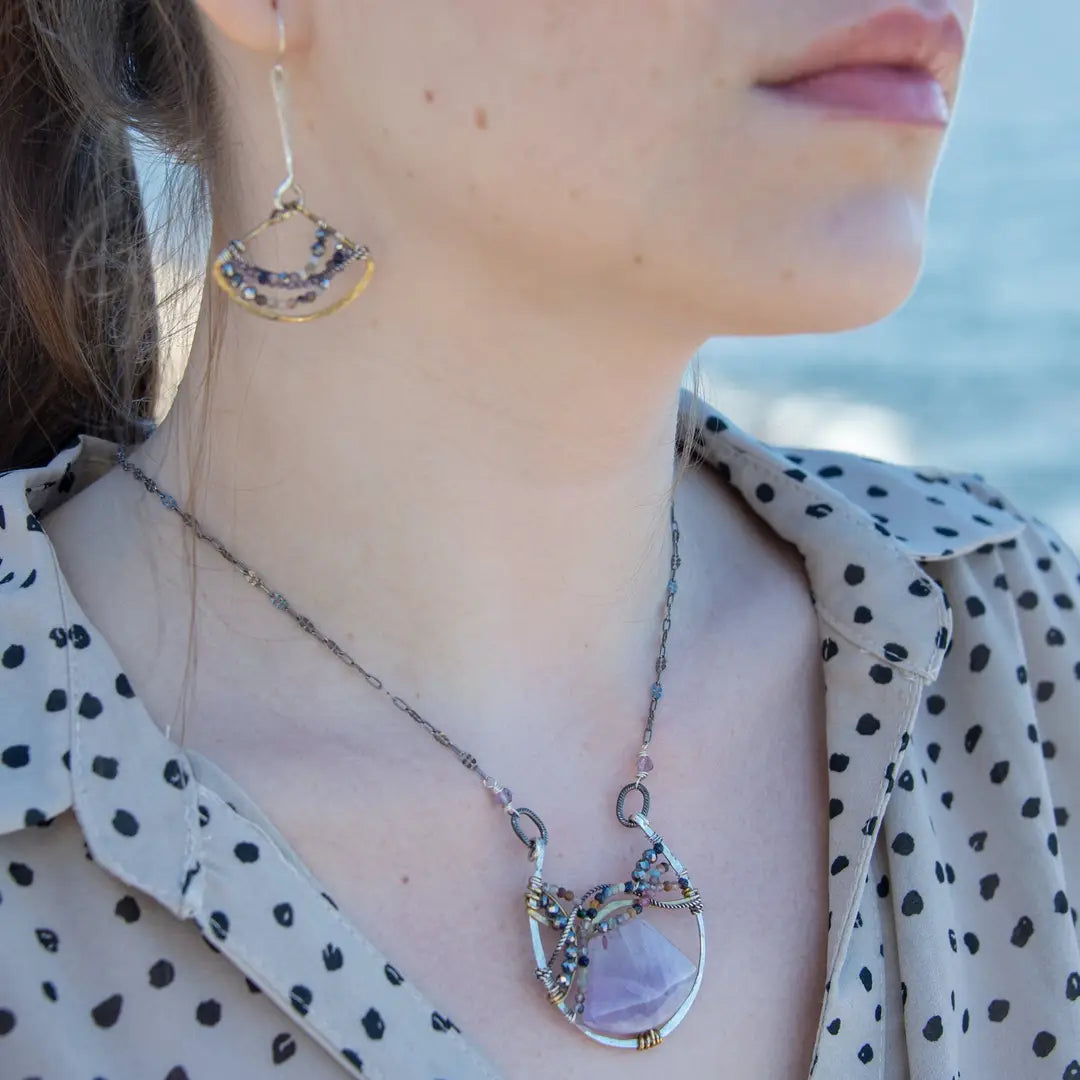 A necklace with a braided design featuring amethyst gemstones and a mix of natural gemstones, with a hammered brass and sterling silver twist. The pendant is accompanied by an oxidized sterling silver chain and a handmade clasp.