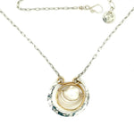 Sterling silver hammered circle pendant with brass circle inside holding a fresh water pearl surrounded by gold filled arches on a sterling silver textured chain