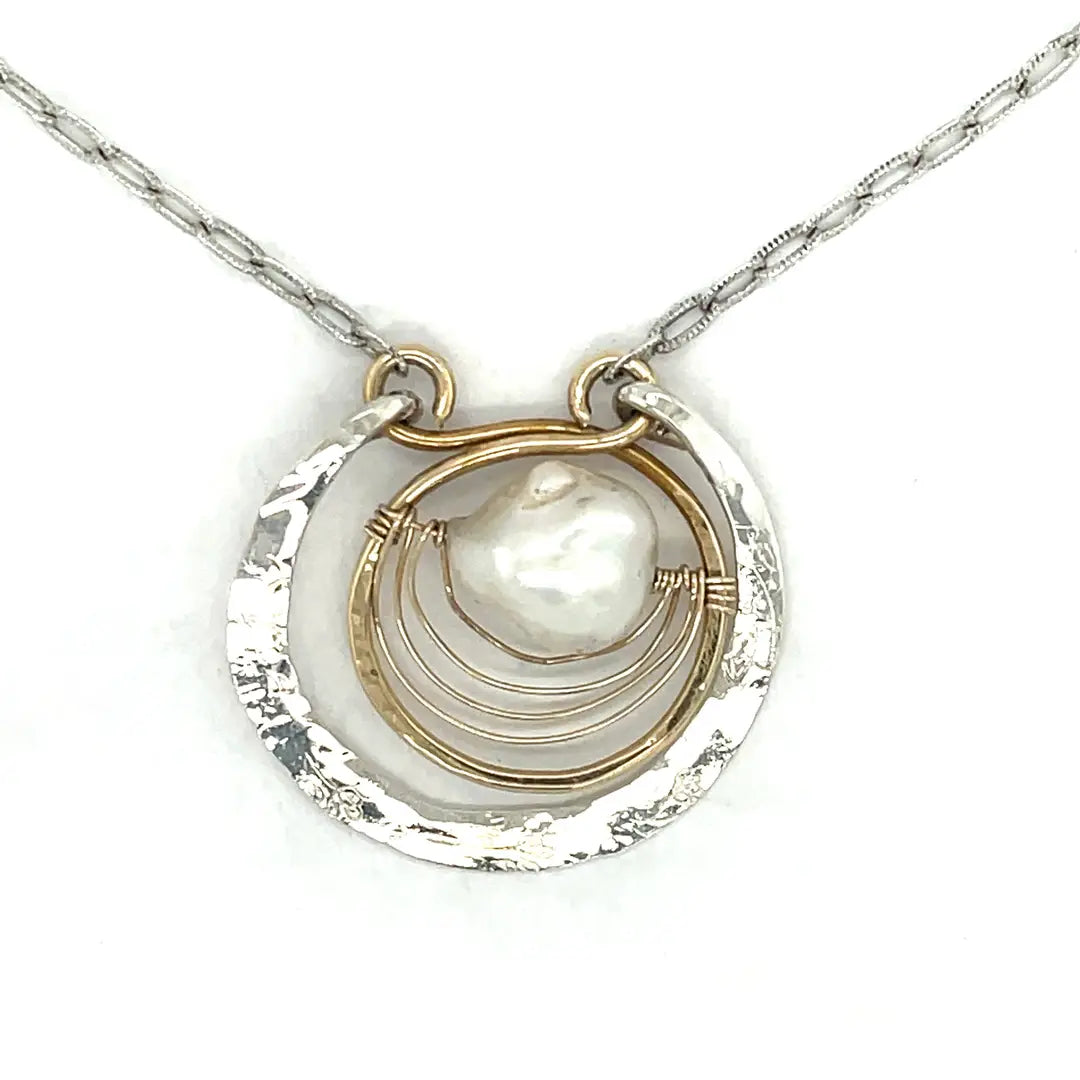 Sterling silver hammered circle pendant with brass circle inside holding a fresh water pearl surrounded by gold filled arches on a sterling silver textured chain