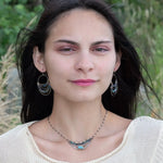 A darkened sterling silver crescent necklace  featuring a bright blue druzy quartz slab and ombre blue tourmaline gemstones on gold filled wire