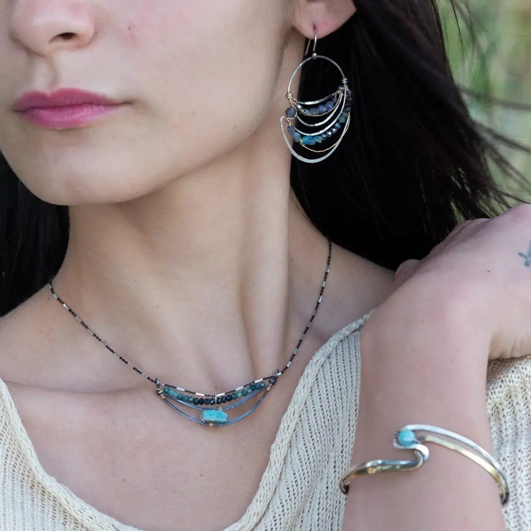 A darkened sterling silver crescent necklace  featuring a bright blue druzy quartz slab and ombre blue tourmaline gemstones on gold filled wire