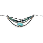 A darkened sterling silver crescent necklace  featuring a bright blue druzy quartz slab and ombre blue tourmaline gemstones on gold filled wire