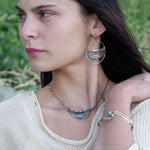 A darkened sterling silver crescent necklace  featuring a bright blue druzy quartz slab and ombre blue tourmaline gemstones on gold filled wire