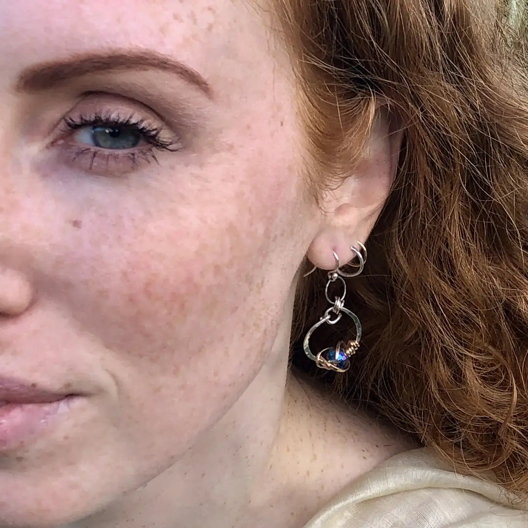 blue crystal built in to a mini sterling silver mini hoop earring wrapped up in bronze wire hanging from a braided link