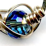 blue crystal built in to a mini sterling silver mini hoop earring wrapped up in bronze wire hanging from a braided link