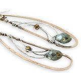 Handmade hammered bronze wings are embellished with sterling silver weaving holding a blue green crystal drop 