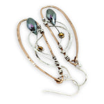 Handmade hammered bronze wings are embellished with sterling silver weaving holding a blue green crystal drop 