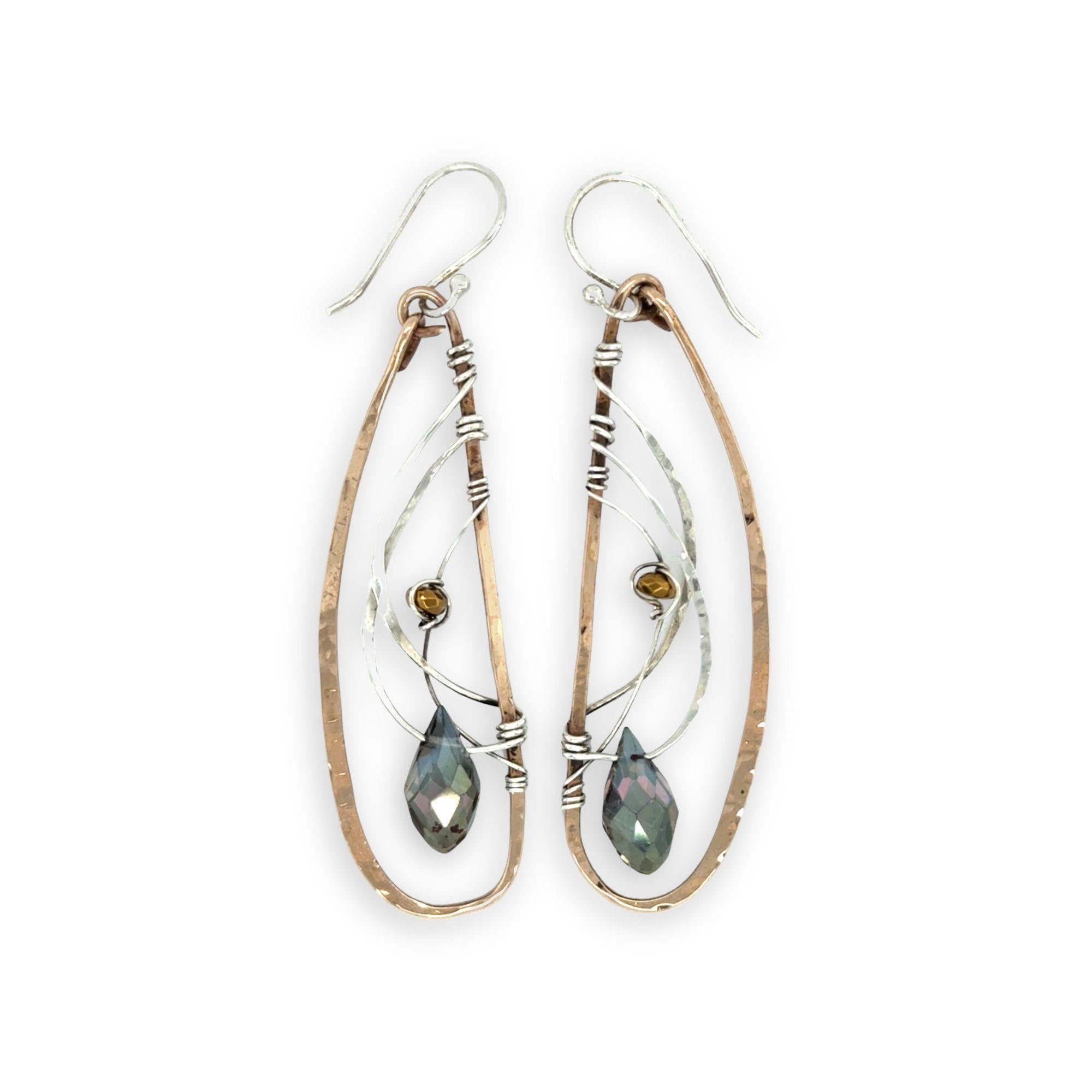 Handmade hammered bronze wings are embellished with sterling silver weaving holding a blue green crystal drop 