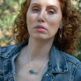 A sterling silver infinity pendant necklace with a twisted silver ring and an adjustable delicate chain. The pendant features apatite faceted gemstone accenting blue crystal.