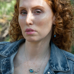 A sterling silver infinity pendant necklace with a twisted silver ring and an adjustable delicate chain. The pendant features apatite faceted gemstone accenting blue crystal.