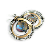 Faceted blue purple crystal coin held inside a nest of oxidized sterling silver wire and thick brass wire earrings