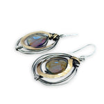 Faceted blue purple crystal coin held inside a nest of oxidized sterling silver wire and thick brass wire earrings