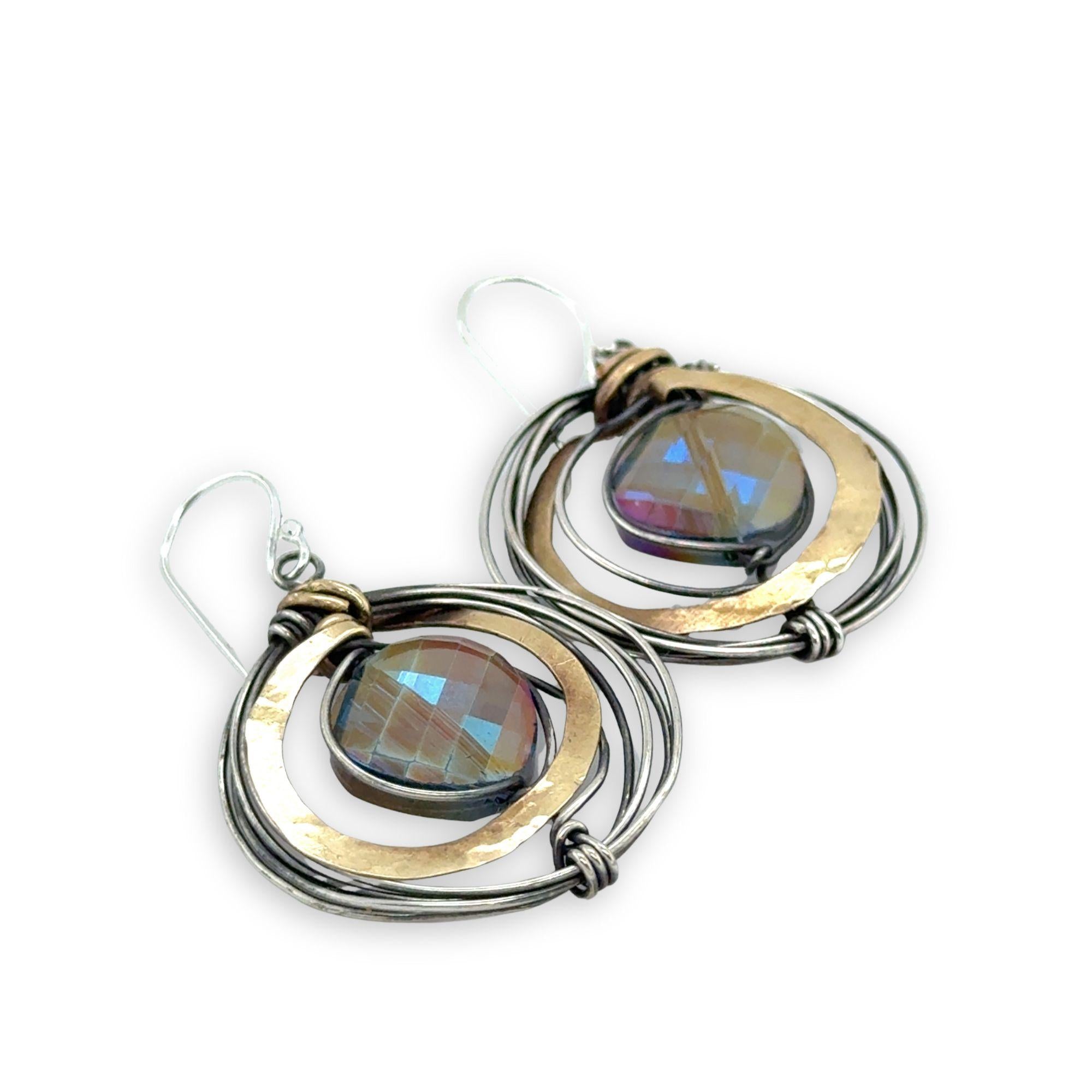 Faceted blue purple crystal coin held inside a nest of oxidized sterling silver wire and thick brass wire earrings