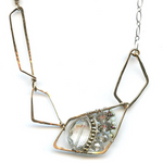 A faceted clear quartz oval gemstone is layered with pyrite and crystals on sterling silver wire inside a bronze parallelogram, then attached to three varying sized parallelograms