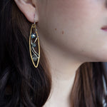 A pair of handmade brass twisted marquise earrings with hammered sterling silver and sparkling crystals in blue, green, and grey colors.