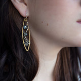 A pair of handmade brass twisted marquise earrings with hammered sterling silver and sparkling crystals in blue, green, and grey colors.