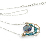 waves of hammered bronze and sterling silver necklace hold a purple-blue crystal coin with chrysocolla and apatite gemstone accentsv