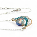 waves of hammered bronze and sterling silver necklace hold a purple-blue crystal coin with chrysocolla and apatite gemstone accents