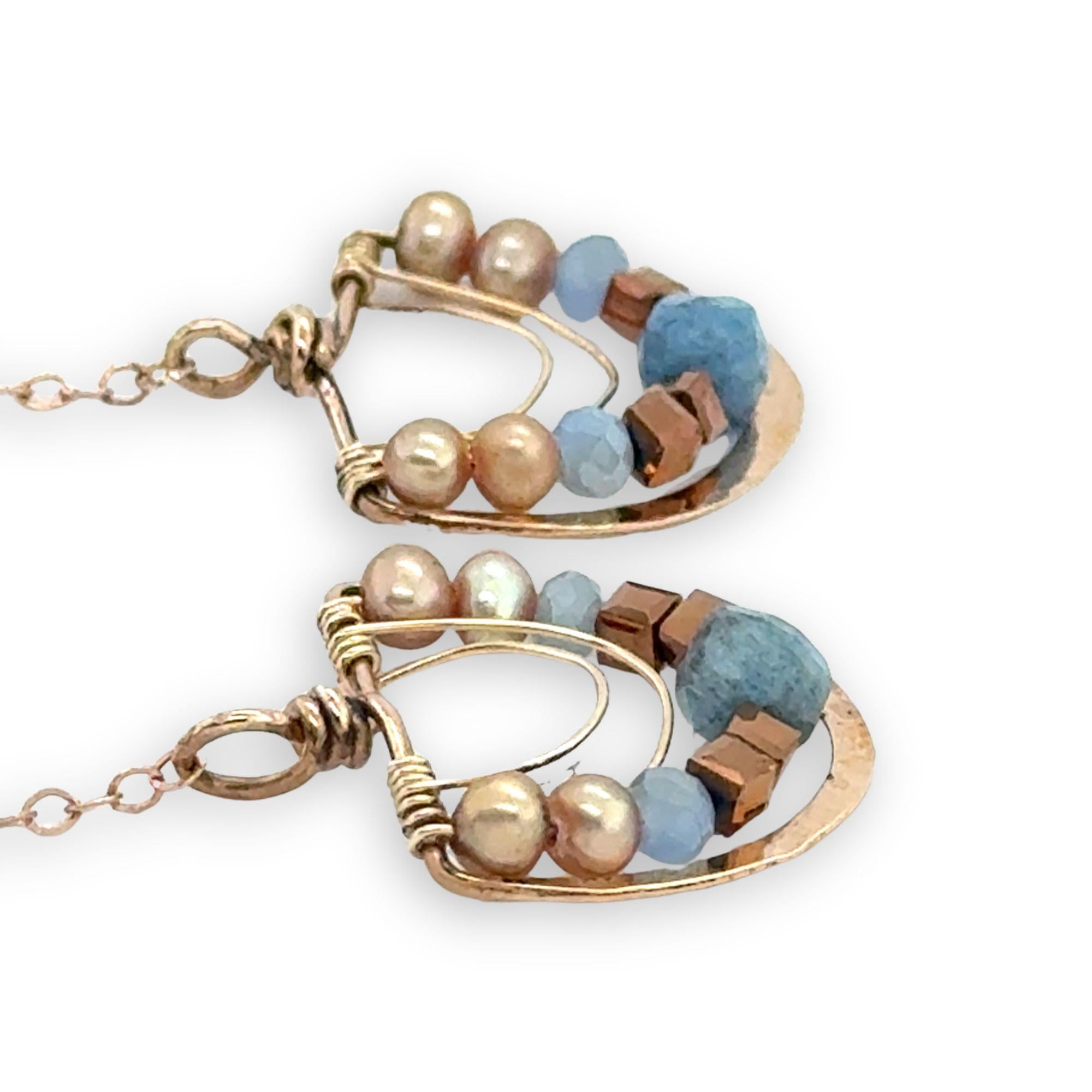bronze semi circles hanging from find rose gold chain, accented with aquamarine cubes, champagne fresh water pearl, blue crystal and copper crystal cubes
