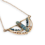 Aquamarine smooth slab is held in the center of a bronze semi circle necklace that's lined with champagne fresh water pearl and aquamarine faceted gemstones on rose gold chain necklace
