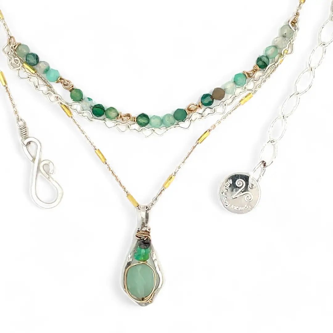 A mini sterling silver pendant with jade and green opal gemstones on gold filled wire hanging from a triple layer chain, with green onyx gemstones, sterling silver heart chain and gold fill accented chain necklace
